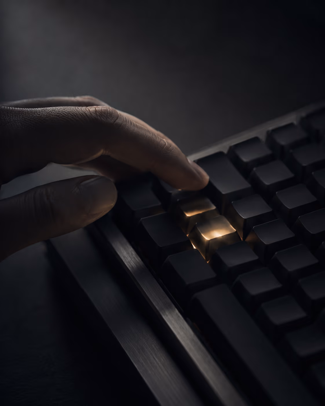 Mão sobre teclado escuro com duas teclas alaranjadas