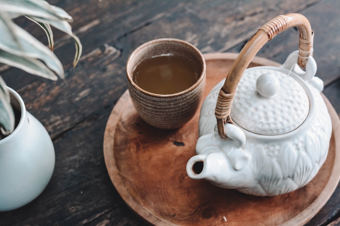 A golden bowl of herbal tea surrounded by fresh botanicals and dried herbs